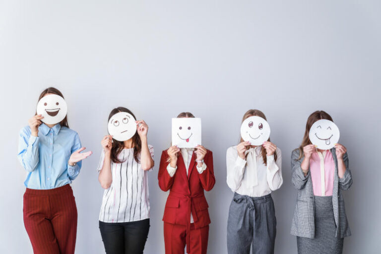 Group of woman covering their faces with drawn emoticons against light background