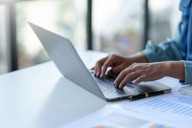 Close-up of a business woman typing a laptop computer on a desk