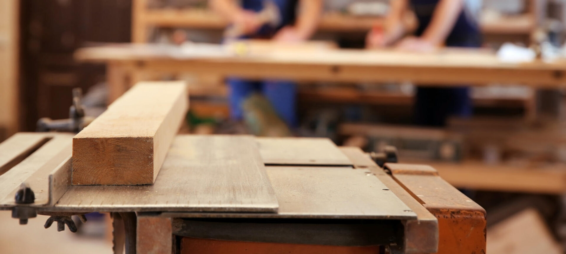 Table in workshop and blurred carpenters on background