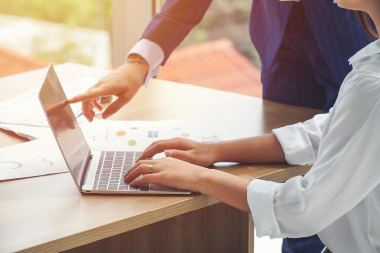 Businesswomen pointing at the laptop screen while her colleague