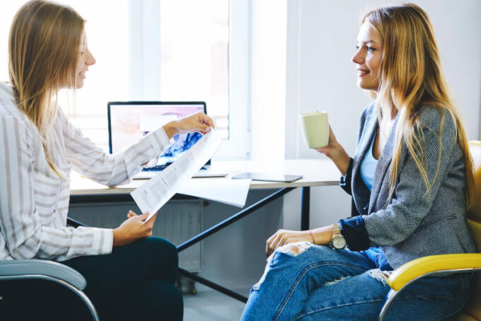 Women coworkers sitting in coworking office near computer with mock up screen