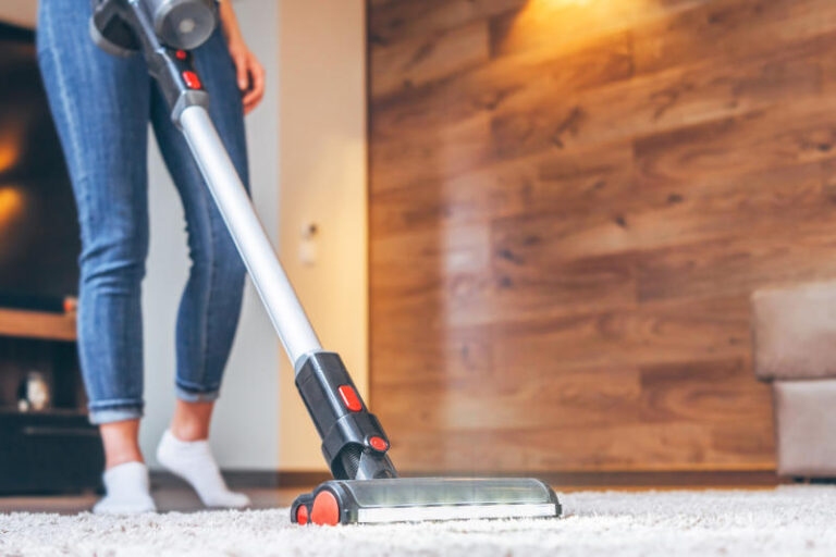 Woman cleaning floor and carpet with cordless vacuum cleaner at home