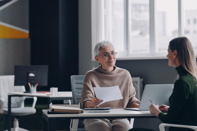 Senior female HR manager having interview with job candidate while sitting at the office desk