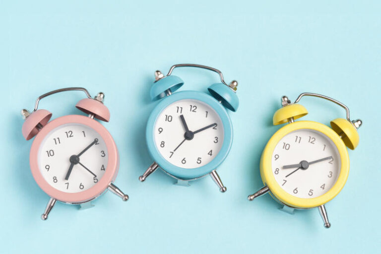 Collection of alarm clocks of different colors show different times Start of the day waking up morning different time zones