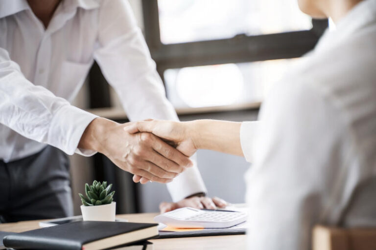 Business executives shaking hands after meeting at office colle