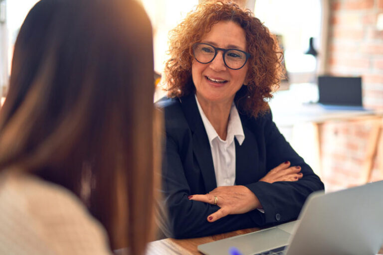 Two beautiful businesswomen smiling happy and confident Sitting with smile on face working together using laptop at the office