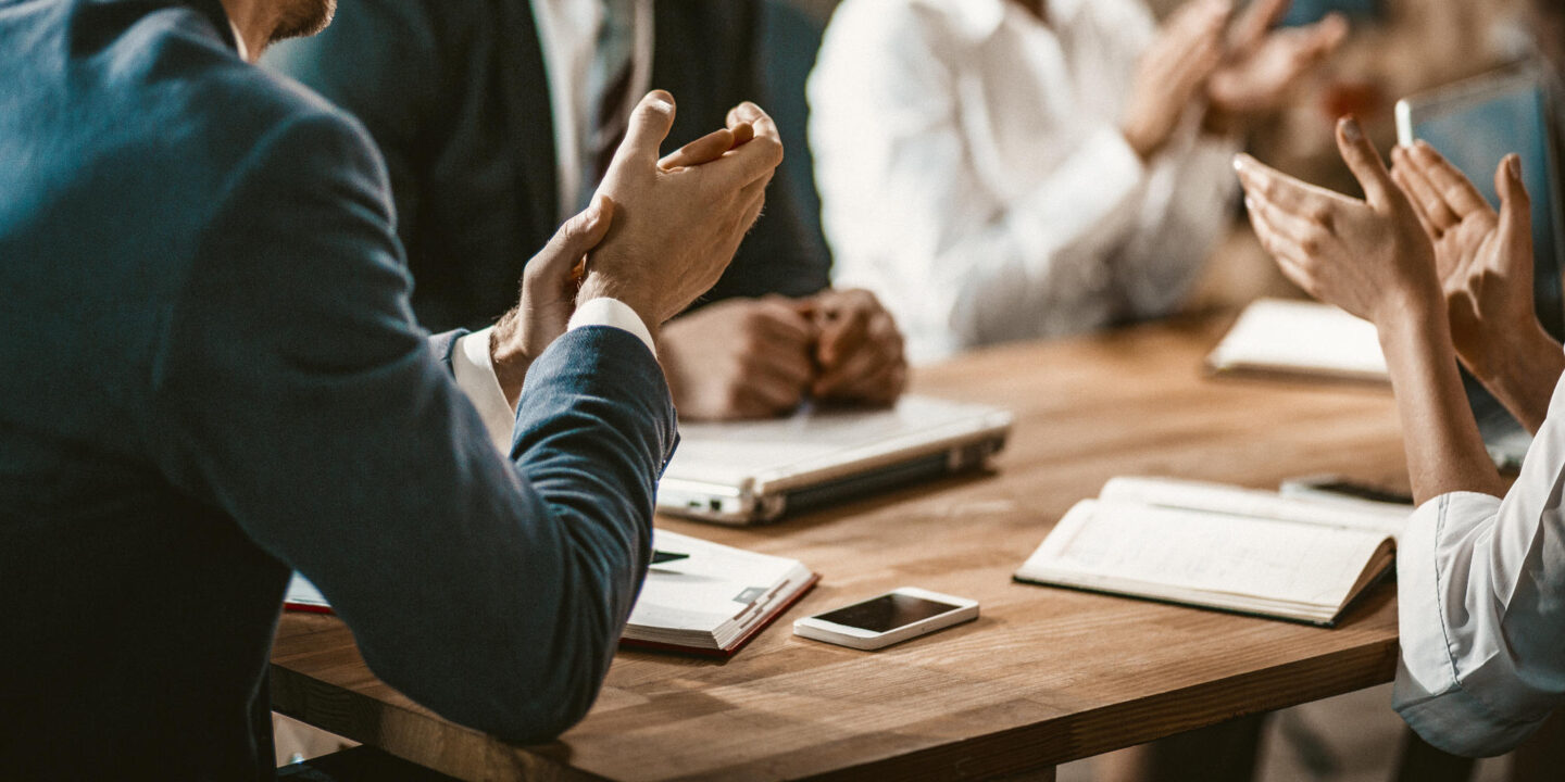 Group of business people applaud during a meeting