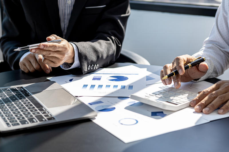 A close-up of the sales manager pressing the white calculator he is examining the sales figures with management to summarize the monthly results and joint planning Sales management concept