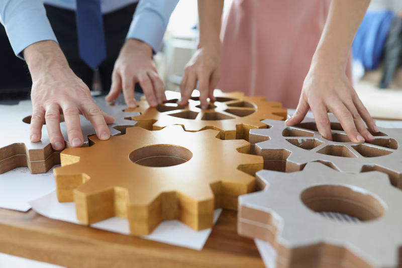 Businesspeople put wooden gears on workplace together work in team