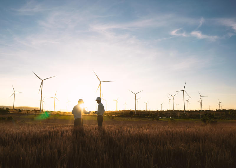 Investors and technicians are standing in talks about wind turbine power generation Wind turbine farm is an alternative electricity source Concept of sustainable resources Renewable energy concept