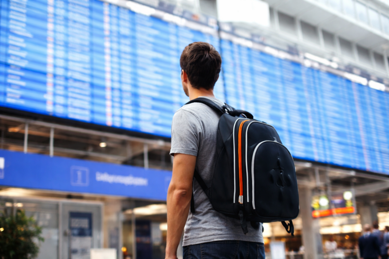 Man seen from the back, looking at an airport screen - IMD Business School