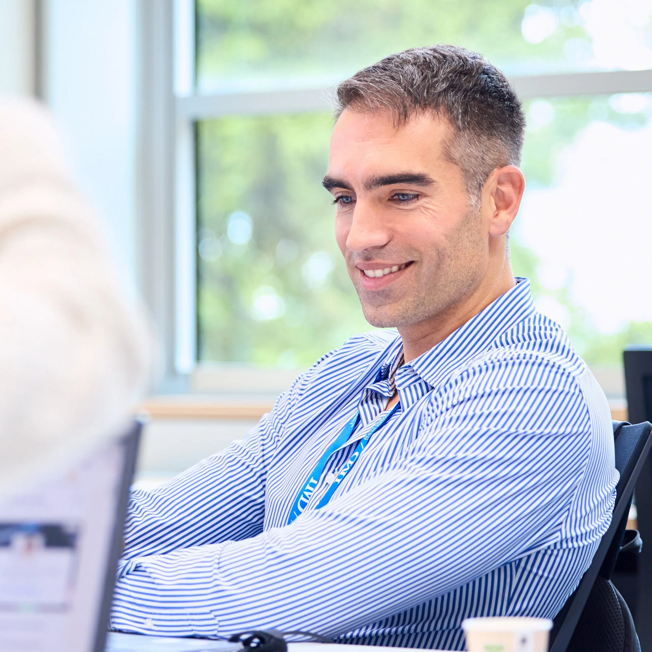 IMD EMBA smiling student participating in class wearing a blue shirt - IMD Business School