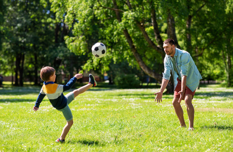 father with little son playing soccer at park