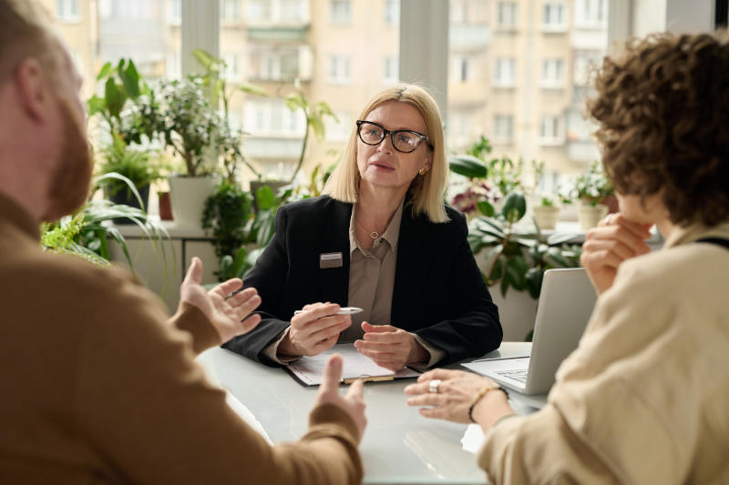 Mature woman consulting couple in insurance agency