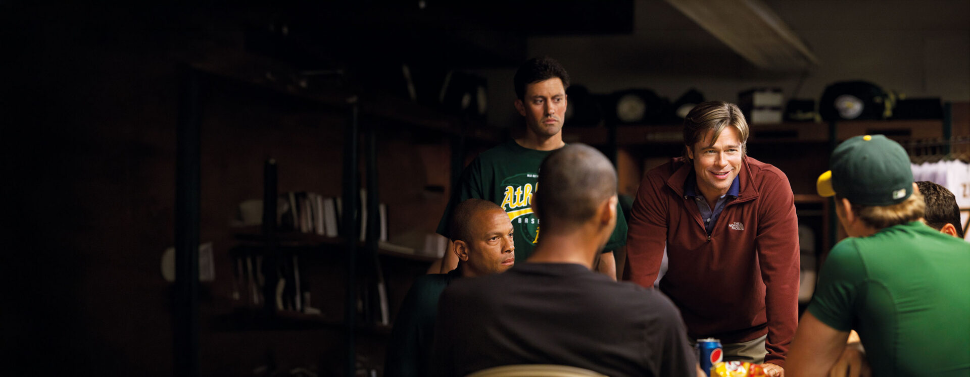 Locker room scene from Moneyball showing a coach leading his baseball team