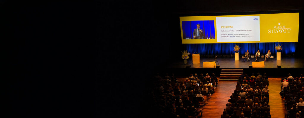 Audience attending a Salzburg Summit discussion featuring David Bach and Justin Trudeau on stage - IMD Business School - IMD Business School