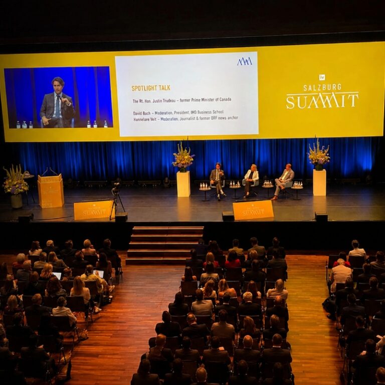 Audience attending a Salzburg Summit discussion featuring David Bach and Justin Trudeau on stage