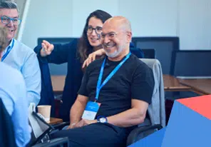 A diverse group of colleagues in a conference room, smiling and chatting during a meeting. - IMD Business School