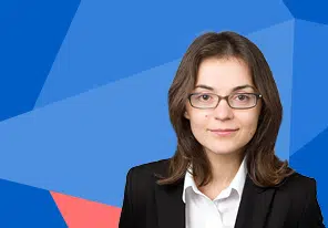 Professional woman portrait: woman with glasses in a black blazer and white shirt, smiling slightly, blue geometric background - IMD Business School