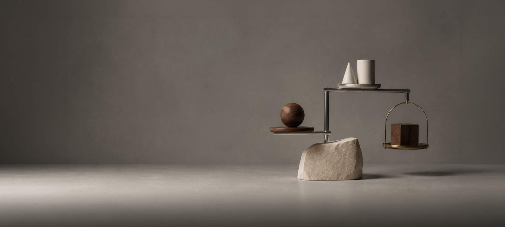 A sophisticated architectural mobile positioned in the right-hand third, composed of three distinct materials: a solid stone form, a cluster of smaller geometric objects, and a finely engineered metal framework