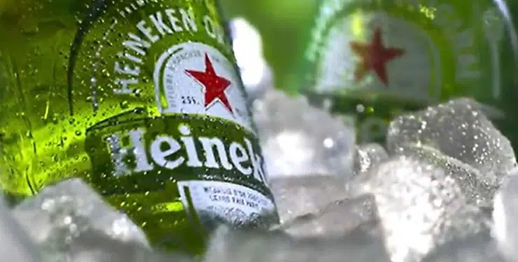 Green Heineken beer bottle chilling on ice with condensation and a red star logo - IMD Business School