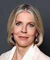 Professional headshot of a smiling blonde woman in a light blazer against a dark background. - IMD Business School