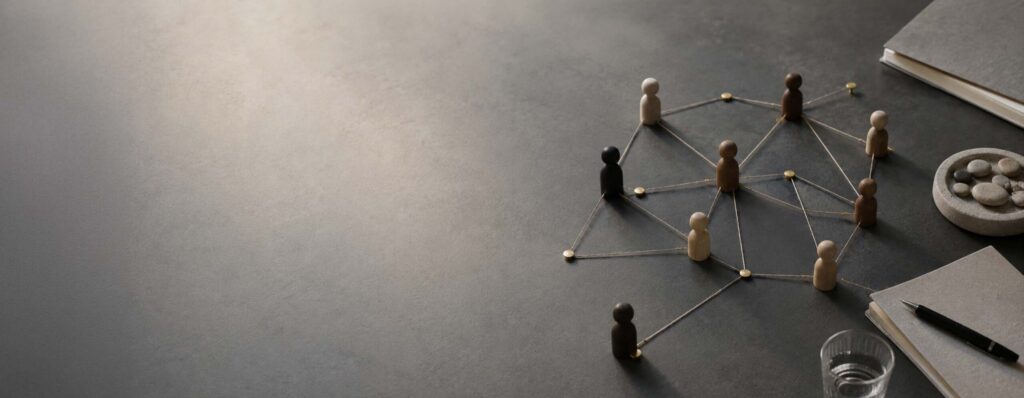 Wooden figurines connected by strings forming a social network on a desk surface, symbolizing collaboration and community. - IMD Business School - IMD Business School
