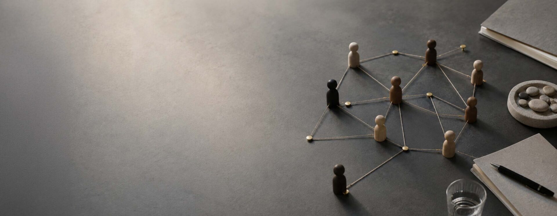 Wooden figurines connected by strings forming a social network on a desk surface, symbolizing collaboration and community.