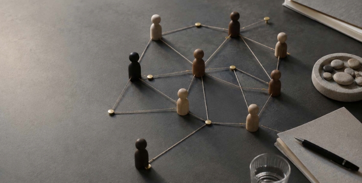 Wooden Figurine Network Diagram Wooden figurines connected by strings forming a social network on a desk surface, symbolizing collaboration and community.