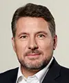 Professional headshot of a middle-aged man with short dark hair and a light beard, wearing a navy blazer and white shirt. - IMD Business School