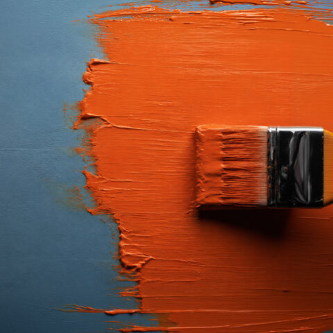 Blue wall being painted with orange paint
