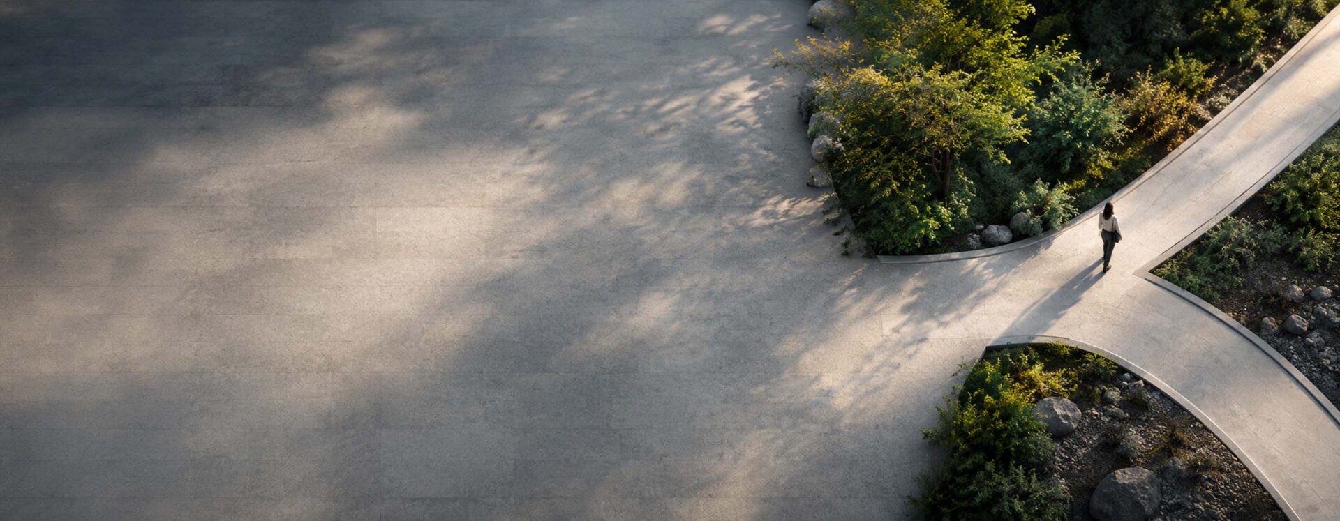 High-angle aerial view of a person walking along a curved pathway split by lush greenery, symbolizing conscious leadership choices and navigating organizational change