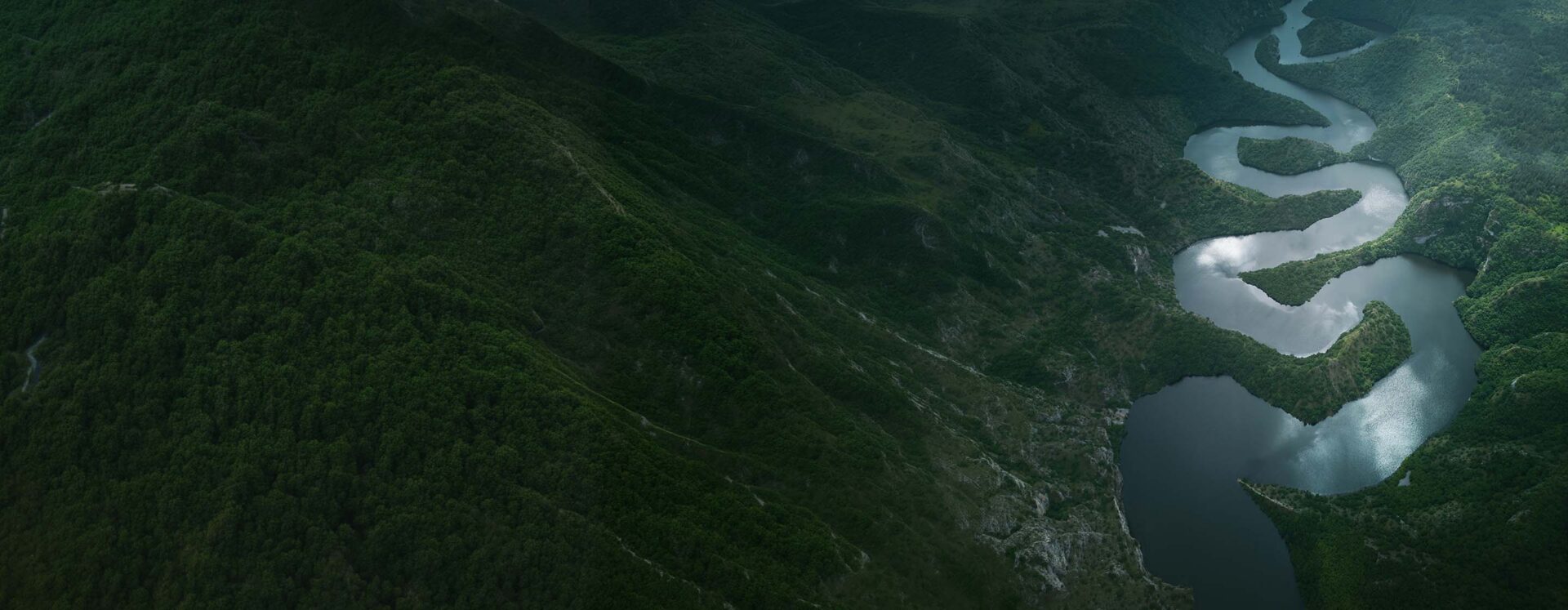 aerial view of a river weaving through a mountainous landscape, illustrating how feedback and information rarely move directly through an organization, but are shaped by relationships, trust, and perceived risk