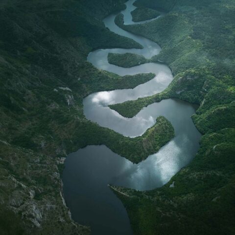 aerial view of a river weaving through a mountainous landscape, illustrating how feedback and information rarely move directly through an organization, but are shaped by relationships, trust, and perceived risk