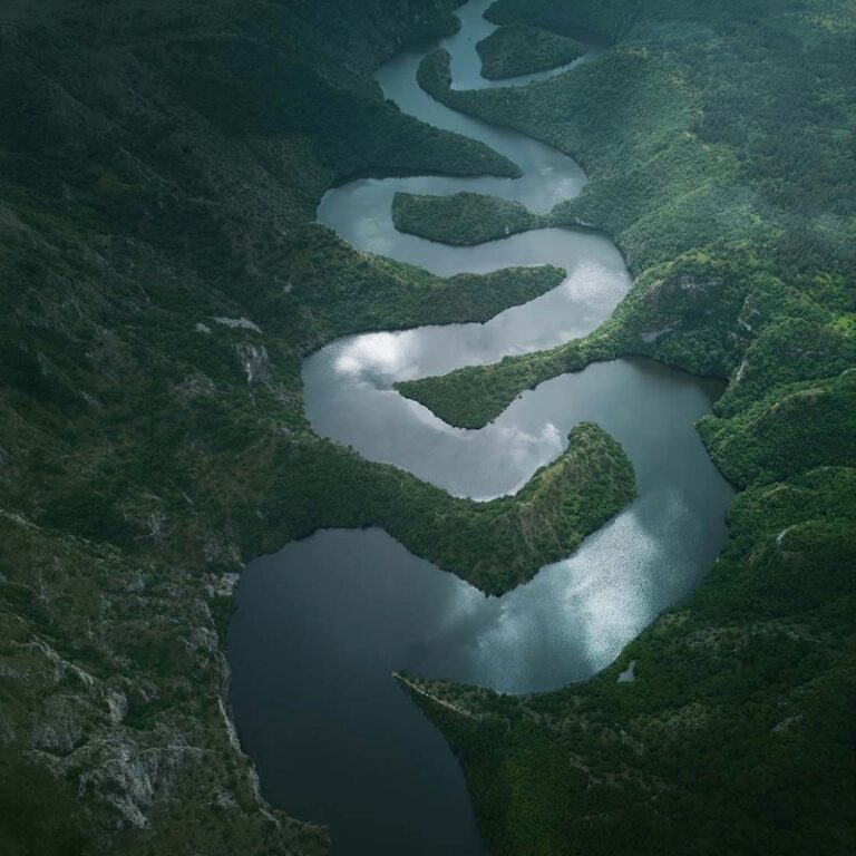 aerial view of a river weaving through a mountainous landscape, illustrating how feedback and information rarely move directly through an organization, but are shaped by relationships, trust, and perceived risk