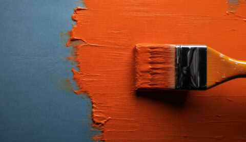 Blue wall being painted with orange paint