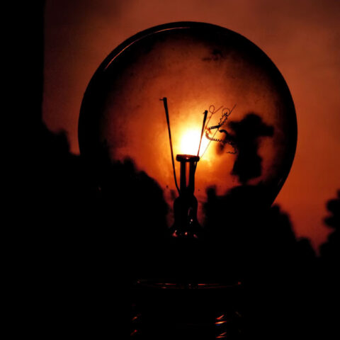 A lit incandescent light bulb glowing warmly in a dark setting.