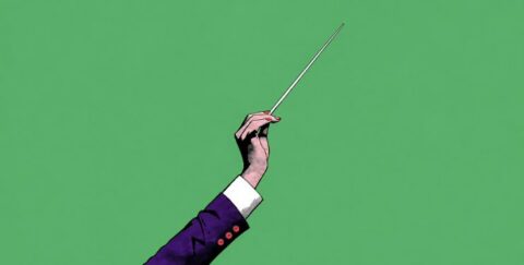 Hand holding a conductor’s baton against a green background, symbolizing the shift from individual expertise to leading and empowering a team